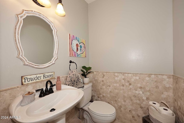 bathroom featuring toilet, sink, and tile walls