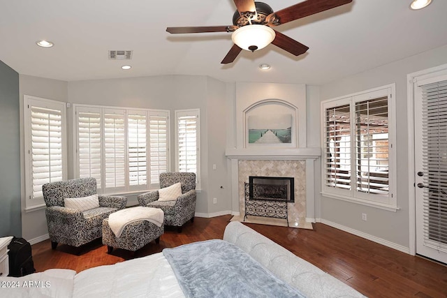 living room with ceiling fan, dark hardwood / wood-style flooring, plenty of natural light, and a tiled fireplace