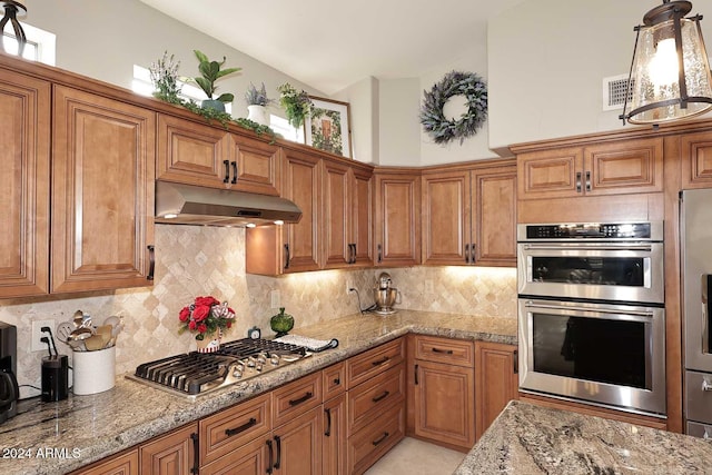 kitchen with decorative backsplash, pendant lighting, stainless steel appliances, and light stone counters