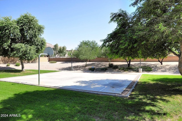 view of property's community with a lawn and basketball court