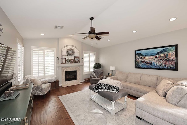 living room featuring ceiling fan, dark hardwood / wood-style flooring, a premium fireplace, and vaulted ceiling