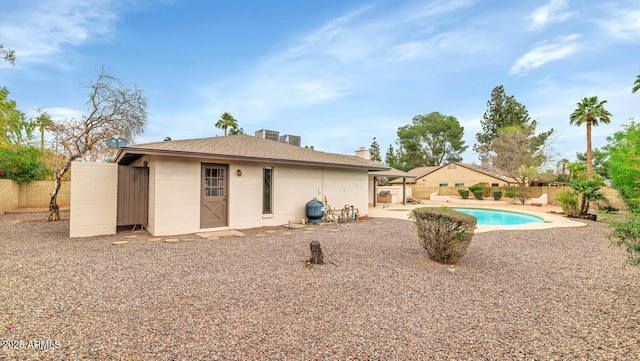 rear view of property featuring a fenced in pool, a patio area, an outdoor structure, and a fenced backyard