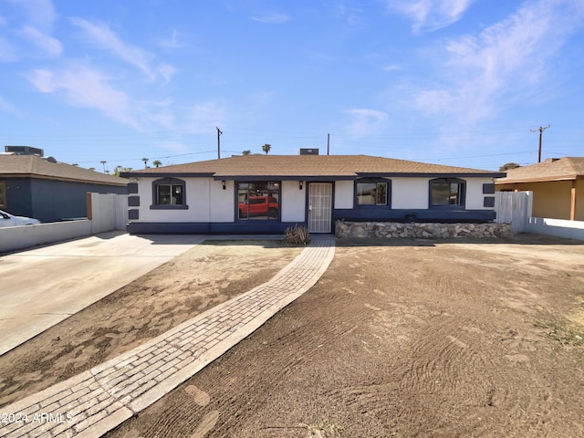 ranch-style home with roof with shingles, stucco siding, and fence