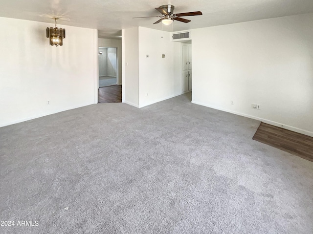 unfurnished room with carpet floors, baseboards, visible vents, and ceiling fan with notable chandelier
