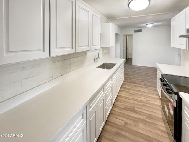 kitchen with white cabinetry, visible vents, a sink, electric stove, and light wood finished floors