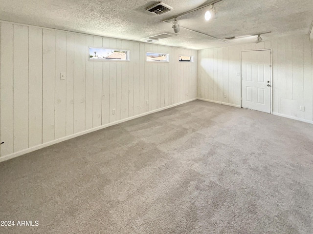 below grade area with a textured ceiling, wood walls, carpet flooring, and visible vents