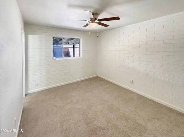 carpeted spare room with brick wall, a textured ceiling, and ceiling fan