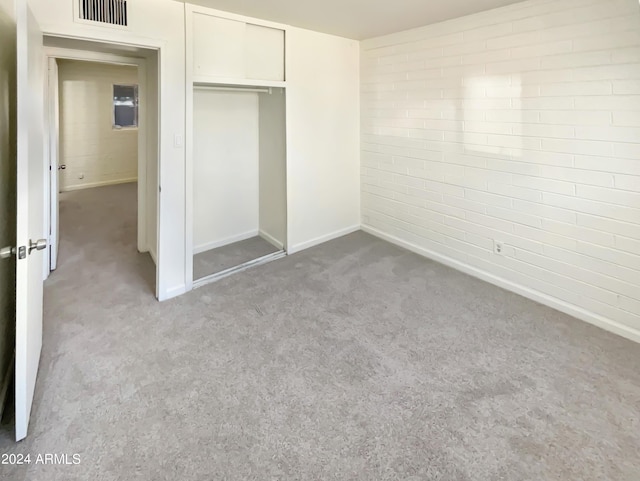 unfurnished bedroom featuring visible vents, baseboards, carpet, and brick wall