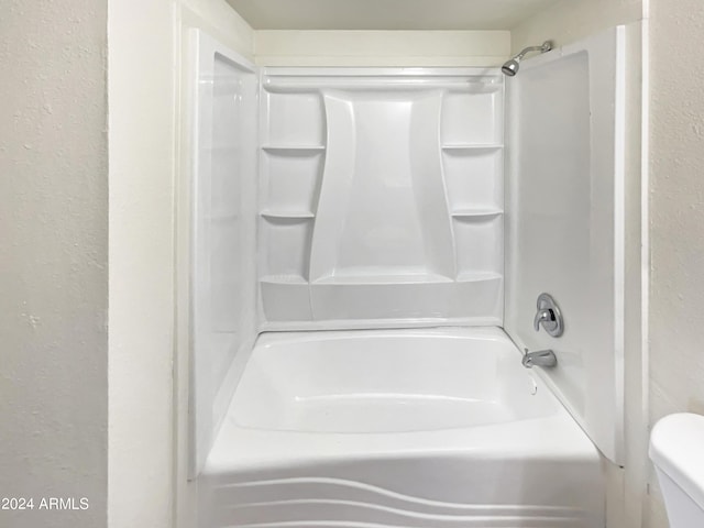 full bathroom with a textured wall and toilet