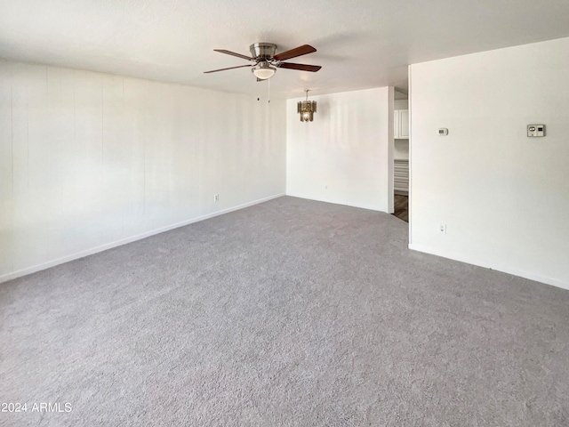 spare room with dark colored carpet and ceiling fan