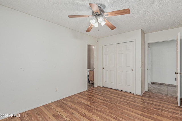 4207 W Soft Wind Dr, Glendale, AZ 85310 - unfurnished bedroom featuring wood finished floors, a textured ceiling, a closet, baseboards, and a ceiling fan