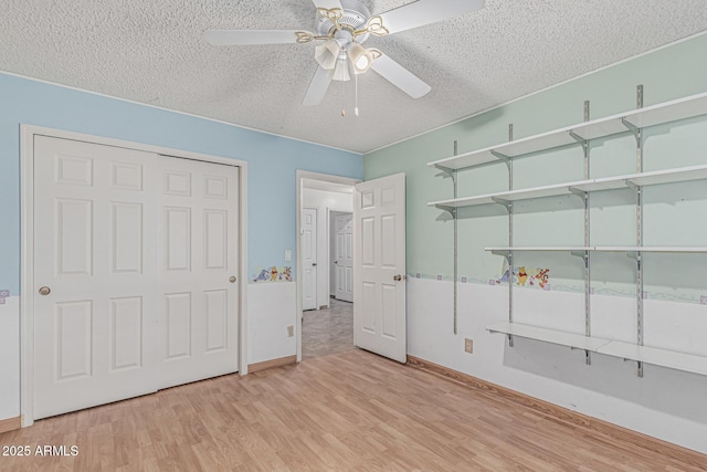 4207 W Soft Wind Dr, Glendale, AZ 85310 - unfurnished bedroom featuring wood finished floors, a textured ceiling, baseboards, a ceiling fan, and a closet