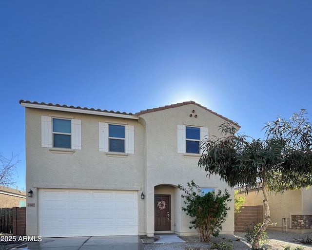 mediterranean / spanish-style home featuring fence, a tiled roof, an attached garage, and stucco siding