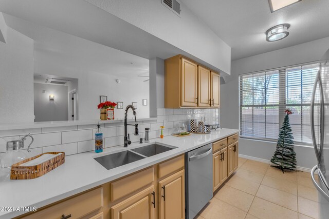 kitchen featuring sink, light brown cabinetry, light tile patterned floors, dishwasher, and decorative backsplash