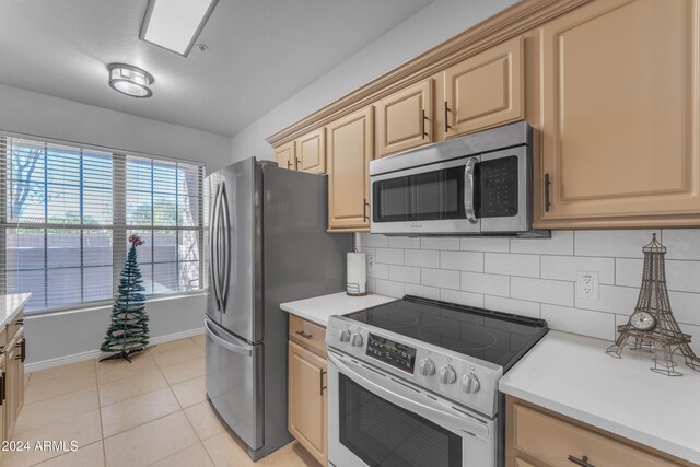 kitchen with stainless steel appliances, light brown cabinetry, light tile patterned flooring, and tasteful backsplash