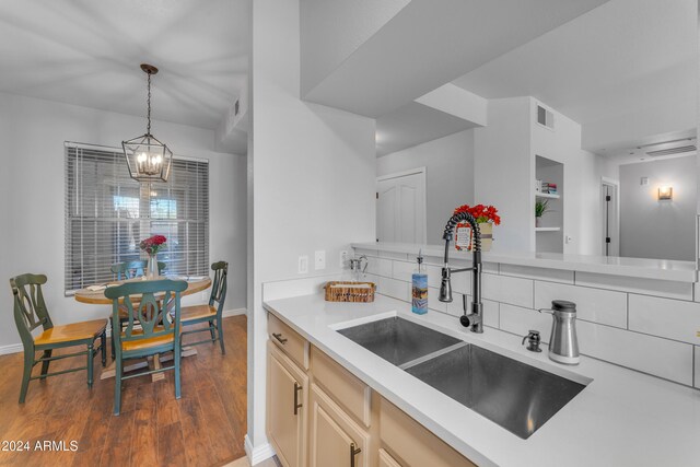 kitchen featuring tasteful backsplash, a notable chandelier, pendant lighting, sink, and dark wood-type flooring