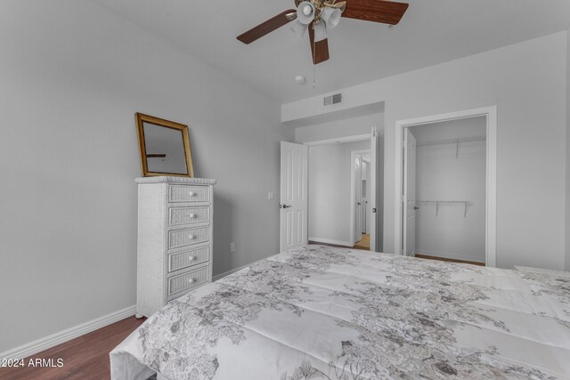 unfurnished bedroom featuring dark hardwood / wood-style flooring, ceiling fan, a walk in closet, and a closet