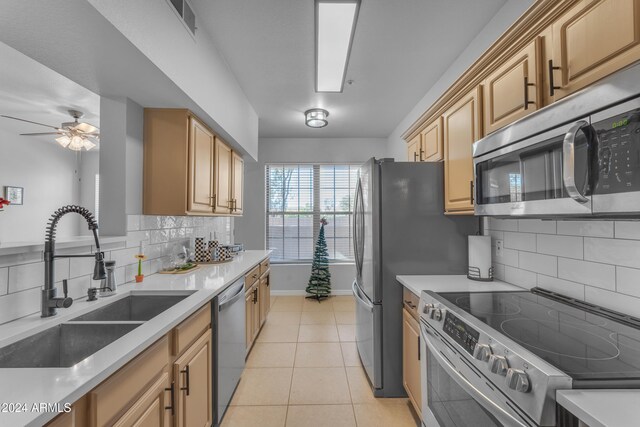 kitchen with stainless steel appliances, light tile patterned flooring, sink, light brown cabinetry, and decorative backsplash