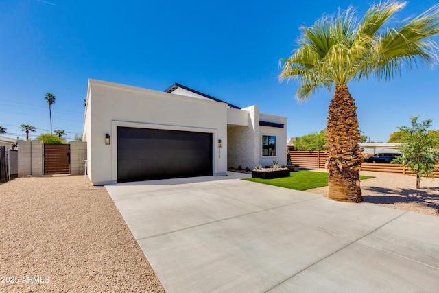 modern home featuring fence, an attached garage, stucco siding, a gate, and concrete driveway