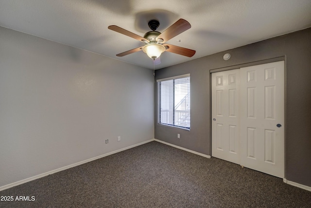 unfurnished bedroom with ceiling fan, dark carpet, and a closet