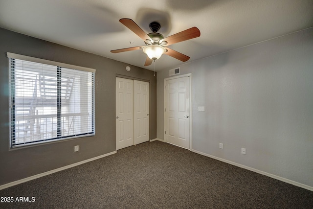 unfurnished bedroom featuring dark carpet, a closet, and ceiling fan
