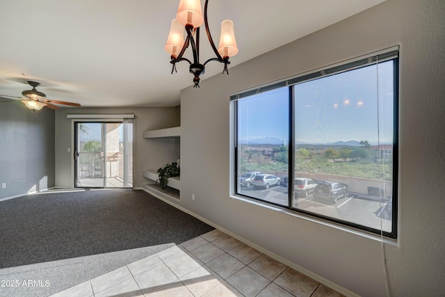 carpeted empty room featuring ceiling fan with notable chandelier