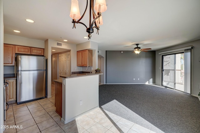 kitchen with decorative light fixtures, light carpet, stainless steel fridge, kitchen peninsula, and ceiling fan with notable chandelier