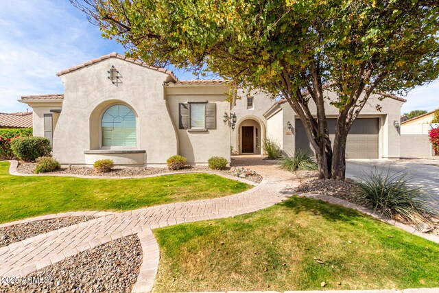 mediterranean / spanish home featuring an attached garage, driveway, a tiled roof, stucco siding, and a front lawn