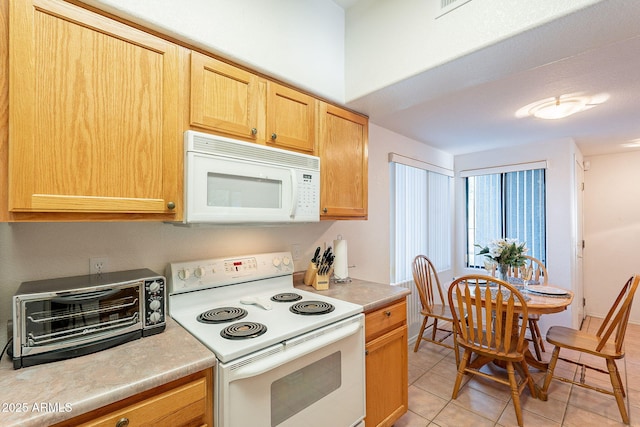 kitchen featuring light countertops, white appliances, a toaster, and light tile patterned floors