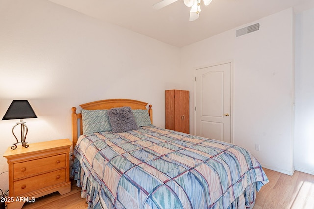 bedroom featuring baseboards, ceiling fan, visible vents, and wood finished floors