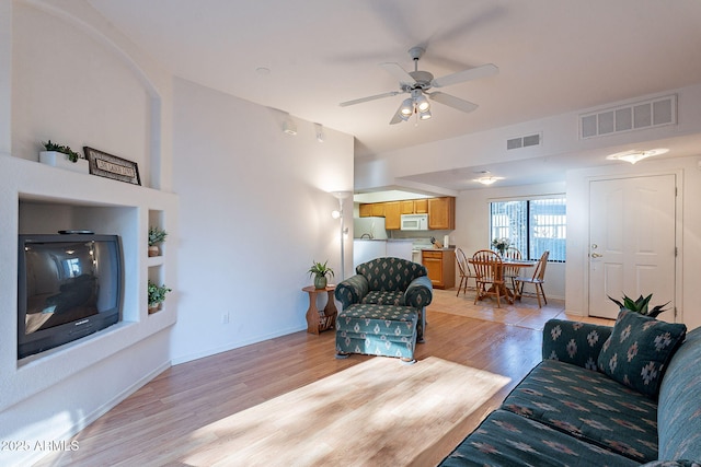 living room with light wood-style floors, visible vents, ceiling fan, and baseboards