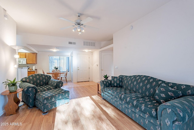 living area featuring light wood finished floors, visible vents, and a ceiling fan