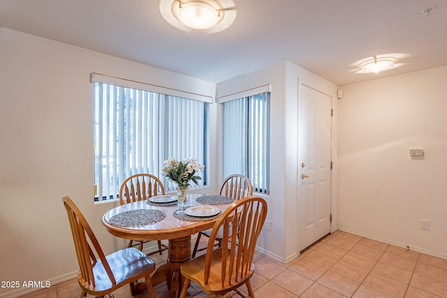 dining room with baseboards, a textured ceiling, and light tile patterned flooring