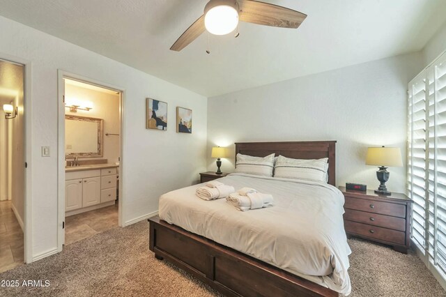 bedroom with light carpet, baseboards, connected bathroom, ceiling fan, and a sink