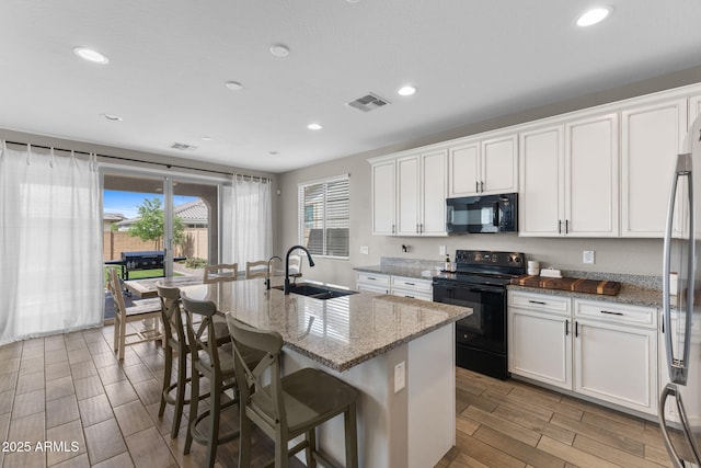 22904 E Domingo Rd, Queen Creek, AZ 85142 - kitchen with black appliances, a sink, wood tiled floors, light stone counters, and recessed lighting