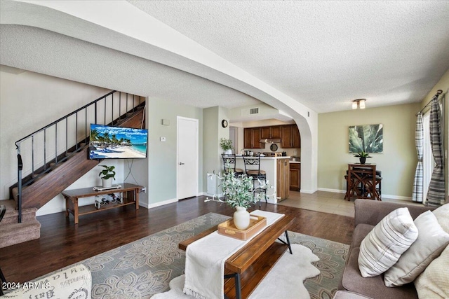 811 E Eugie Ave, Phoenix, AZ 85022 - living area with arched walkways, a textured ceiling, stairway, dark wood-type flooring, and baseboards
