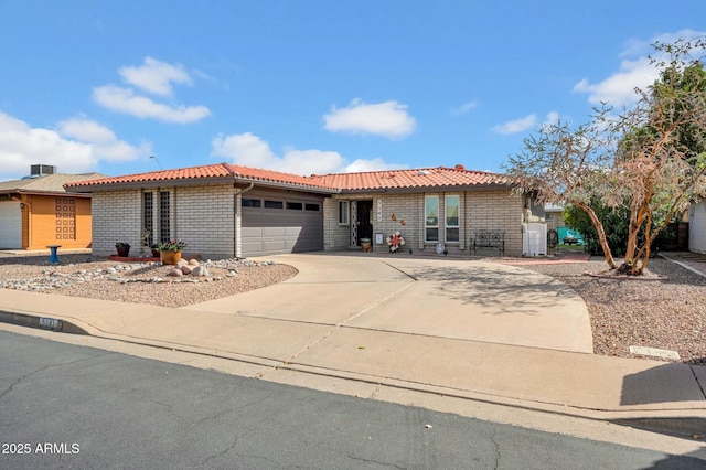 ranch-style home featuring driveway, brick siding, an attached garage, and a tile roof