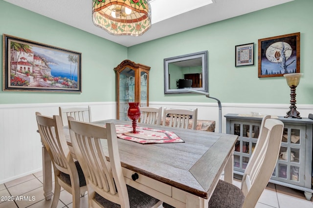 dining room featuring tile patterned flooring and a wainscoted wall