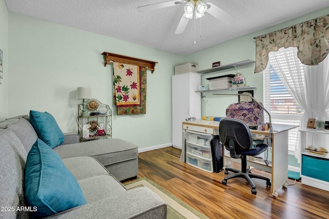 office featuring a ceiling fan, a textured ceiling, baseboards, and wood finished floors