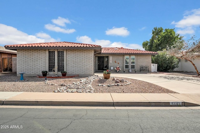 view of front facade featuring a tile roof, concrete driveway, and brick siding