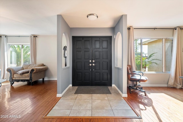 entrance foyer featuring light wood-type flooring, arched walkways, and baseboards