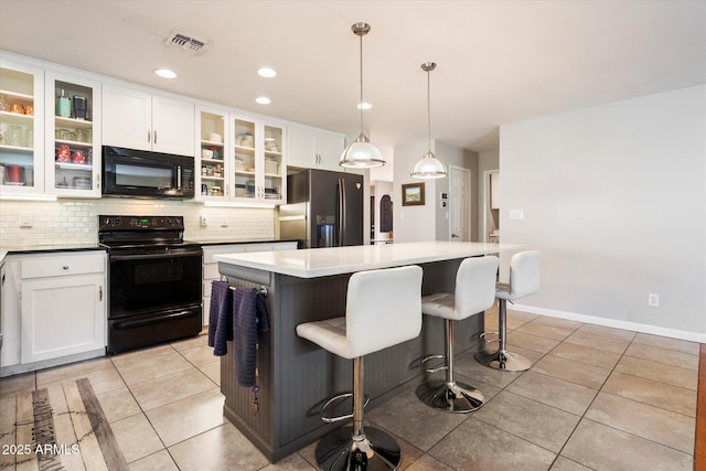 kitchen with light tile patterned floors, decorative backsplash, black appliances, white cabinetry, and a center island