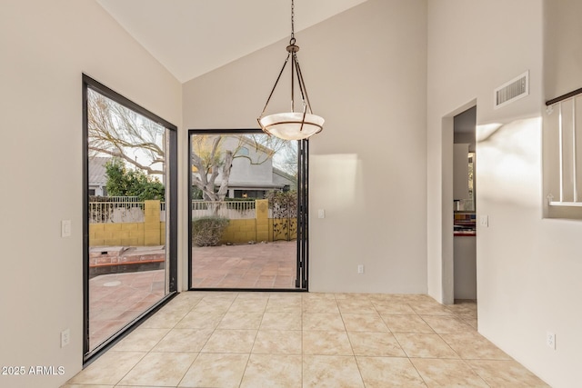 unfurnished dining area featuring light tile patterned floors, visible vents, and high vaulted ceiling