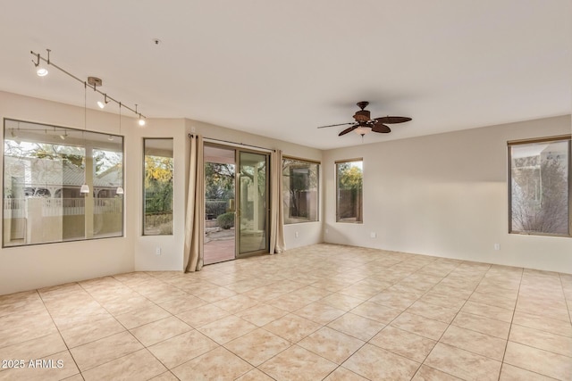 empty room featuring rail lighting, light tile patterned floors, plenty of natural light, and ceiling fan