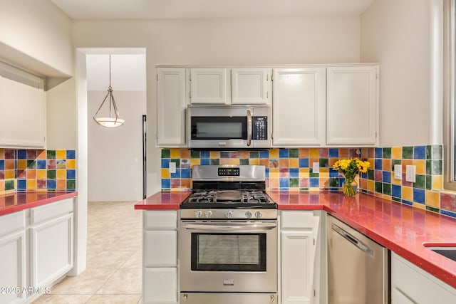 kitchen with stainless steel appliances, white cabinets, backsplash, dark countertops, and pendant lighting