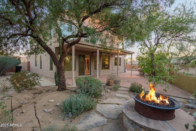 view of front facade with a patio area, fence, a fire pit, and stucco siding