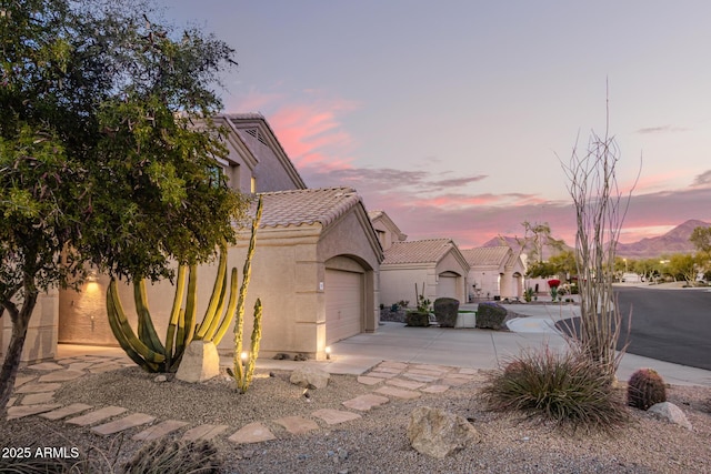 view of front of house featuring a garage, a tile roof, concrete driveway, and stucco siding