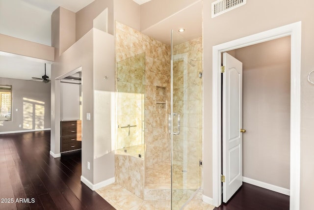 full bath featuring a stall shower, baseboards, visible vents, a ceiling fan, and wood finished floors