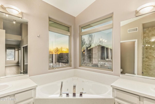 bathroom featuring lofted ceiling, vanity, visible vents, a tub with jets, and a stall shower