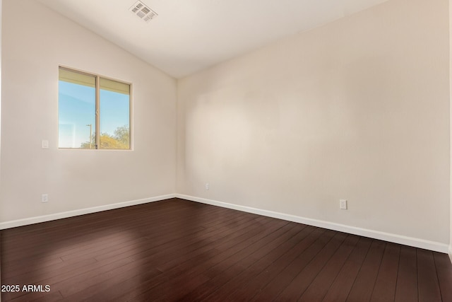 empty room featuring dark wood-type flooring, visible vents, vaulted ceiling, and baseboards